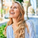 Woman smiling and looking into the distance while walking down a landscaped city street