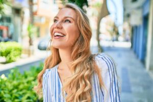 Woman smiling and looking into the distance while walking down a landscaped city street